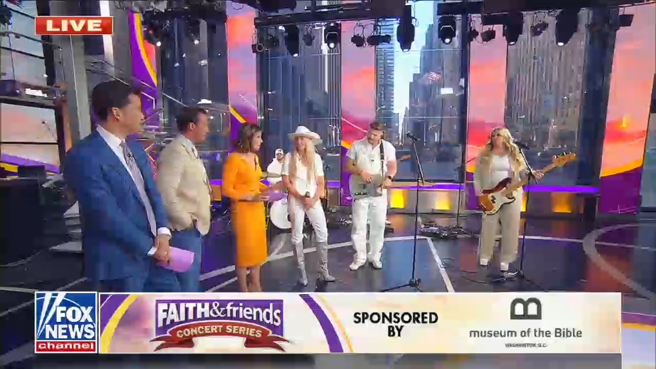 The three members of Cain are standing on the Fox and Friends set dressed in beige and white. One band member is wearing a white cowboy hat. The chyron at the bottom of the screen reads Faith and Friends concert series sponsored by Museum of the Bible 