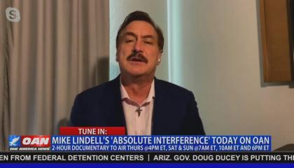 An OAN screenshot of file footage of MyPillow CEO Mike Lindell. Chyron reads "Tune in: Mike Lindell's 'Absolute Interference' today on OAN. 2-hour documentary to air Thurs @4PM ET, Sat & Sun @7AM ET, 10AM ET and 6PM ET"