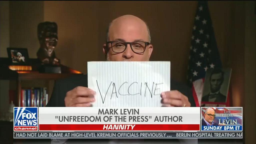 Mark Levin holds up paper in front of his face reading "VACCINE" on it, chyron reads: "Mark Levin unfreedom of the press author"
