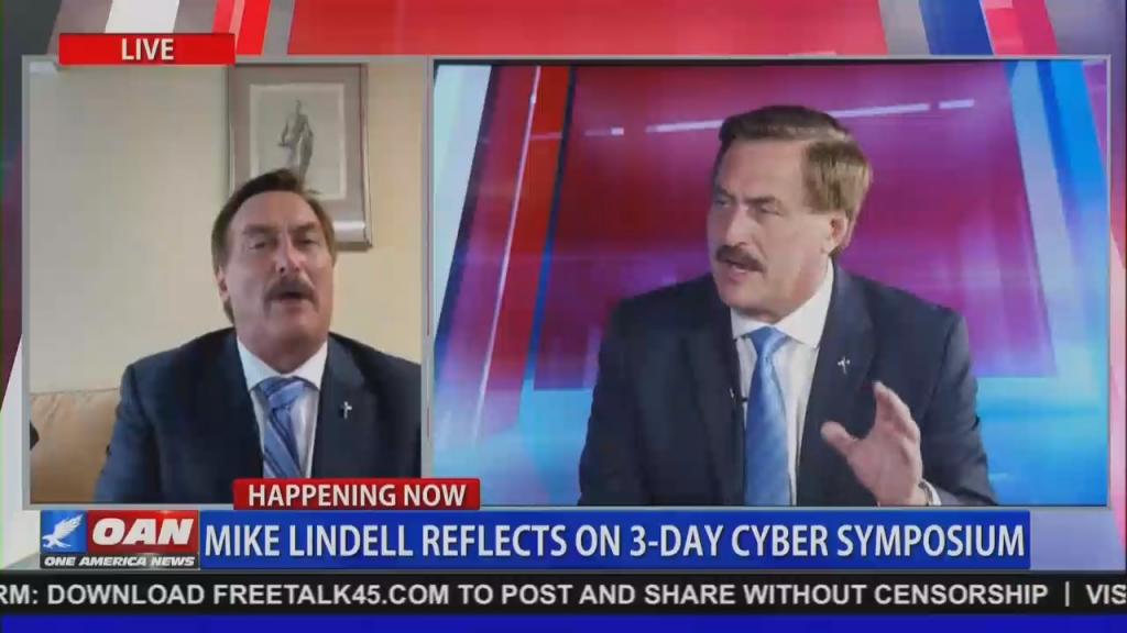 An OAN screenshot of MyPillow CEO Mike Lindell doing a remote interview on screen left, with screen right showing larger file footage of Lindell in a different OAN interview. Chyron reads "Mike Lindell reflects on 3-day Cyber Symposium"